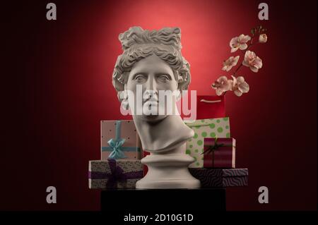 Statue of Apollo Belvedere, flowers and gifts boxes and packages, spotlights and multi-colored backgrounds. Stock Photo