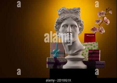 Statue of Apollo Belvedere, flowers and gifts boxes and packages, spotlights and multi-colored backgrounds. Stock Photo