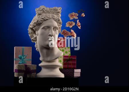 Statue of Apollo Belvedere, flowers and gifts boxes and packages, spotlights and multi-colored backgrounds. Stock Photo