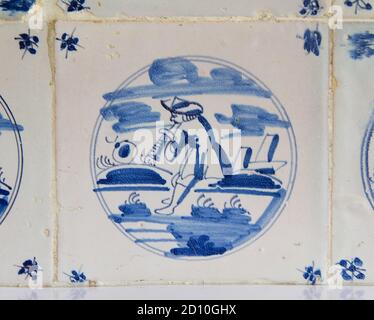 Delft blue and white tile with the painting of a sheperd playing a flute and a sheep Stock Photo