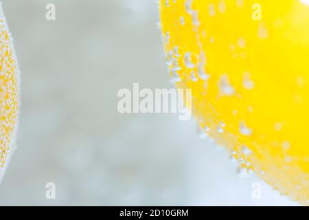 A close up of a lemon, in water and collecting fizzing air bubbles, creating an abstract pattern. Stock Photo