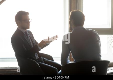 Male colleagues discussing new project ideas indoors. Stock Photo