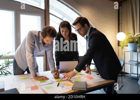 Focused male team leader managing working process with colleagues. Stock Photo