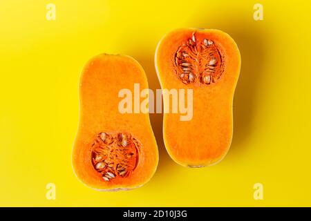 Two halves of butternut squash on yellow background. Seasonal, harvest, fall, organic food, dieting, healthy food concept. Stock Photo