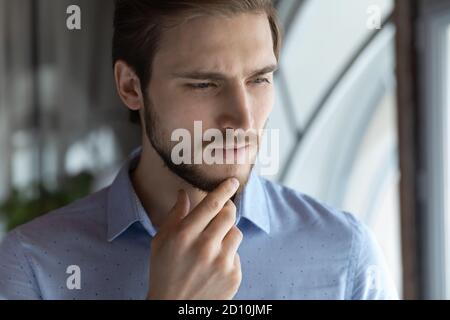 Thoughtful young businessman making difficult choice in office. Stock Photo