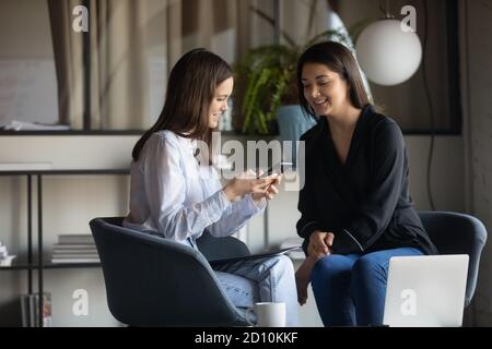 Happy friendly mixed race female colleagues enjoying break pause time. Stock Photo