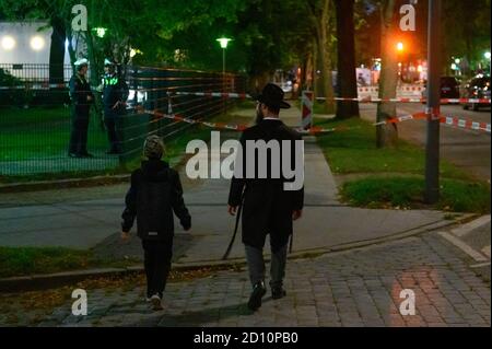 Hamburg, Germany. 04th Oct, 2020. A man and a boy walk towards the cordoned-off area in front of the synagogue. Near the synagogue in Hamburg, an attack occurred on Sunday afternoon in which a 26-year-old man was seriously injured. Credit: Jonas Walzberg/dpa/Alamy Live News Stock Photo