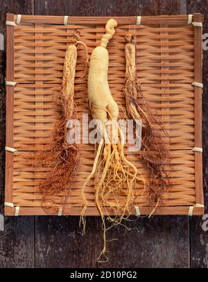 Fresh and dry ginseng on bamboo weave with copy space on the wood background Stock Photo