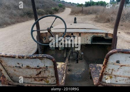 Old 1928 jeep body rusted seats and dashboard while broken down along the side of hiking trail. Stock Photo