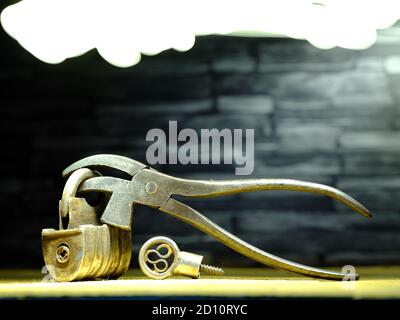 Vintage 1800's Barrel Padlock with screw key and vintage cobblers pliers against slate background Stock Photo