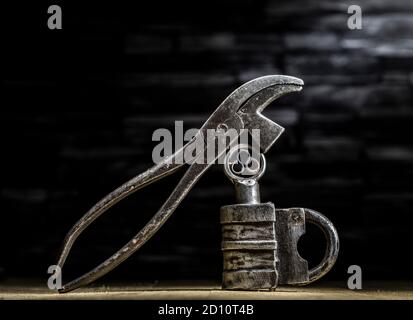 Vintage 1800's Barrel Padlock with screw key and vintage cobblers pliers against slate background Stock Photo