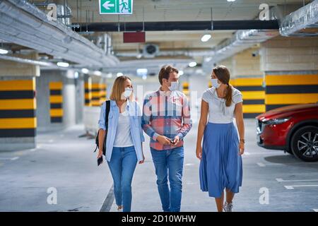 Group of young people in protection masks in underground parking lot Stock Photo