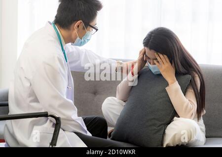 Portait of asian female patient with face mask talking to Psychotherapist doctor for consult about her mental health after stress strain from quaranti Stock Photo