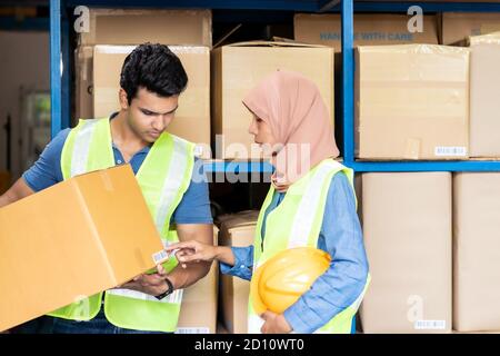 Islam asian warehouse worker working with Indian warehouse worker about inventory and checking on barcode. For business warehouse inventory logistic a Stock Photo