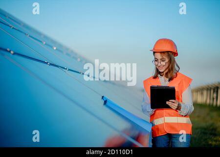Inspector Engineer Woman Holding Digital Tablet Working in Solar Panels Power Farm, Photovoltaic Cell Park, Green Energy Concept Stock Photo