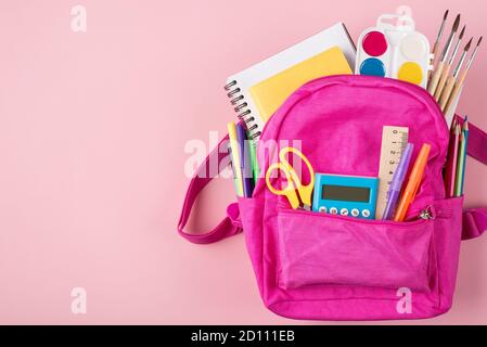 Top above overhead view photo of pink backpack and colorful stationery placed to the right side isolated on pastel pink background with copyspace Stock Photo