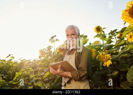 Successful senior farmer in workwear looking at you while reading document Stock Photo