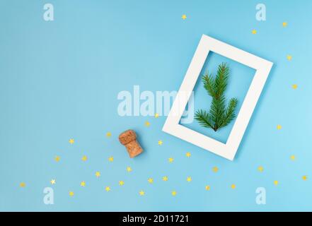 Christmas and New Year composition on a blue background with a champagne bottle cork, a white frame and golden confetti in the shape of a star. Horizo Stock Photo