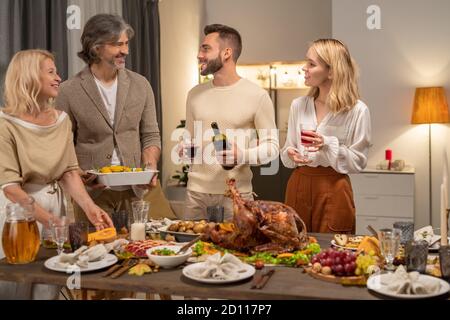 Happy young man with bottle and glass of red wine looking at his parents Stock Photo