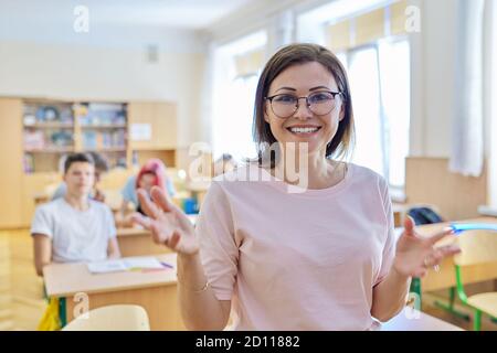 Mature woman teacher talking makes presentation teaches looking at camera Stock Photo