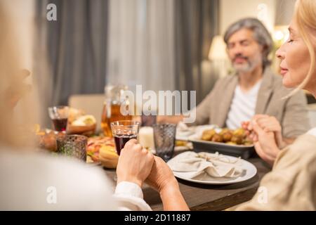 Hands of family members saying thanks to Lord in Thanksgiving prayer by table Stock Photo
