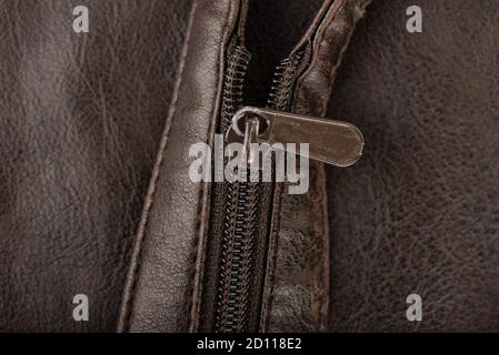 Close-up shot of a zip fastener on a brown belt. The zipper is not fully closed. Stock Photo