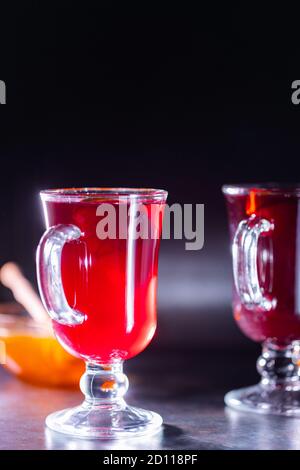 Christmas mulled wine on a dark background. Glass of mulled wine glows in the backlight. Traditional hot drink at Christmas time Stock Photo