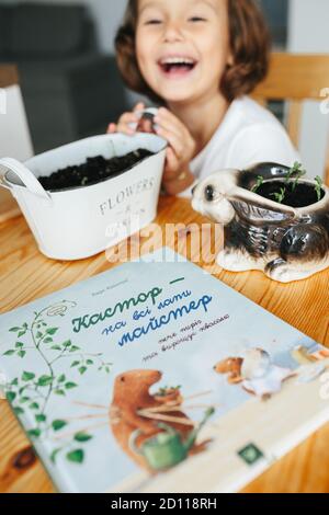 Kiev, Ukraine - 4th October 2020: Kids science experiment - Child reading favorite book Castor Harvey the Gardener on ukrainian learning grow seeds at Stock Photo