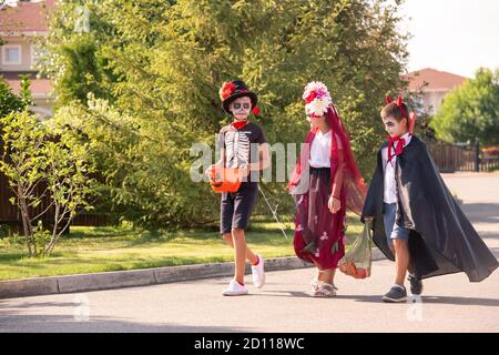 Group of little friends with painted faces in halloween costumes having chat Stock Photo