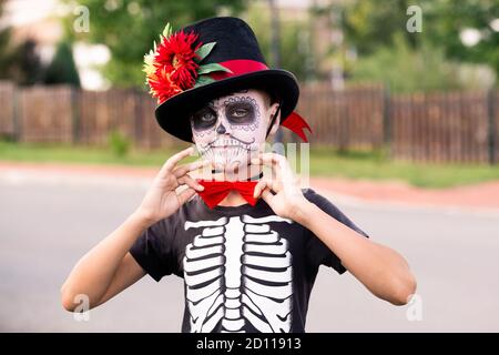 Halloween boy with painted face in costume of skeleton with hat and red bowtie Stock Photo