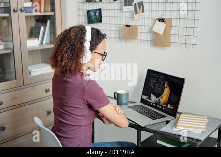 Young mixed-race diligent student having online lesson in home environment Stock Photo