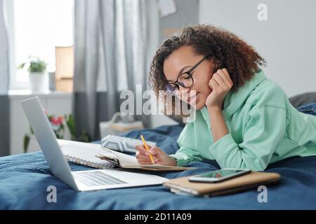 Young contemporary female student in eyeglasses looking through her notes Stock Photo