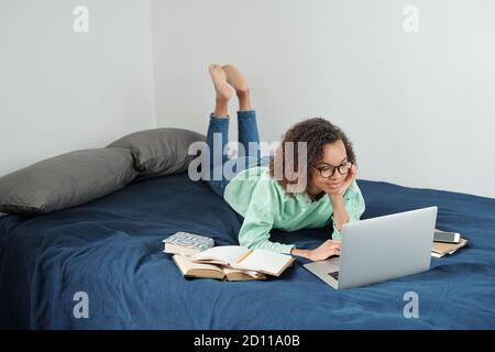 Young relaxed female student in jeans and hoodie preparing for forthcoming exams Stock Photo