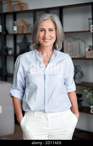 Smiling elegant confident middle aged woman standing in office, portrait. Stock Photo