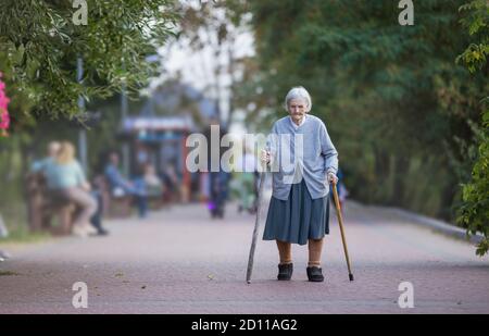 Senior woman with two canes walking in park Stock Photo