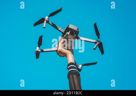 Woman hand holding DJI Mavic 2 Pro drone or quadcopter isolated on the blue sky background. 29.09.2020, Netherlands, Amsterdam Stock Photo