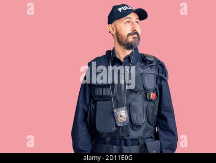 Young handsome man wearing police uniform smiling looking to the side and staring away thinking. Stock Photo