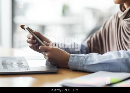Female hands holding smartphone and using laptop Stock Photo