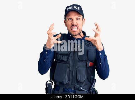 Young handsome man wearing police uniform shouting frustrated with rage, hands trying to strangle, yelling mad Stock Photo