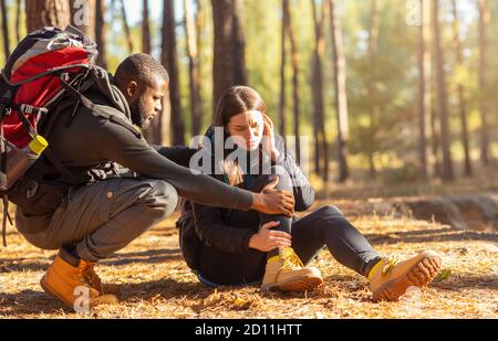 Black man comforting his injured woman, hiking together Stock Photo