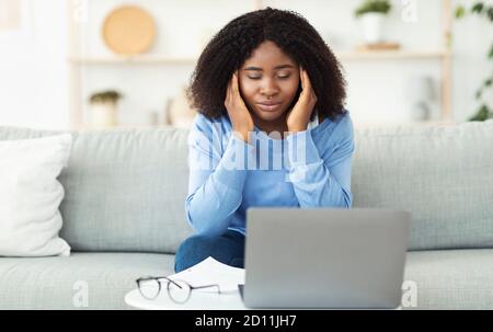 Tired black lady touching and massaging temples Stock Photo