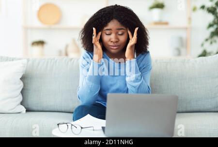 Tired african american lady touching and massaging temples Stock Photo