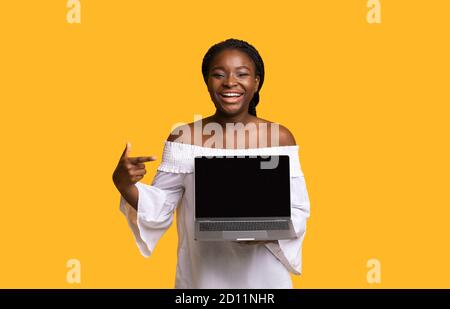 Check This Website. Cheerful Black Lady Pointing At Laptop With Black Screen Stock Photo