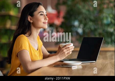 Happy young lady using laptop at cafe Stock Photo