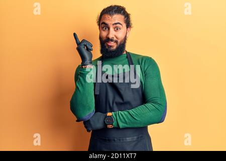 Young arab man wearing barber apron smiling happy pointing with hand and finger to the side Stock Photo