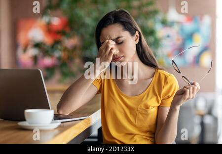 Tired young woman student sitting in front of laptop Stock Photo