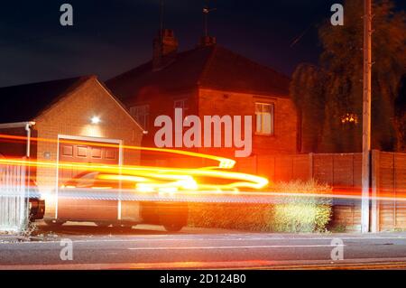 Light trails of a vehicle on a residential street at night. Stock Photo