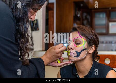 woman putting makeup on another woman for a party of the day of the dead Stock Photo
