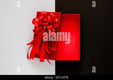 Red christmas box with red bow ribbon on black and white background. Black Friday concept. Stock Photo