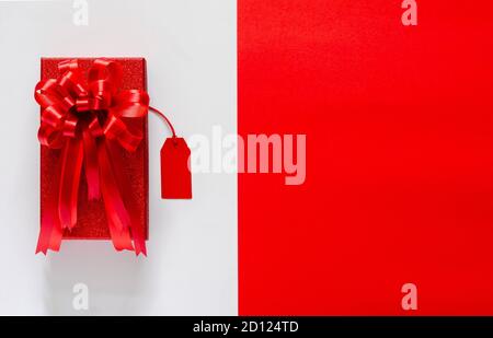 Red christmas box with red bow ribbon and price tag on white and red background. Black Friday and Cyber Monday concept. Stock Photo